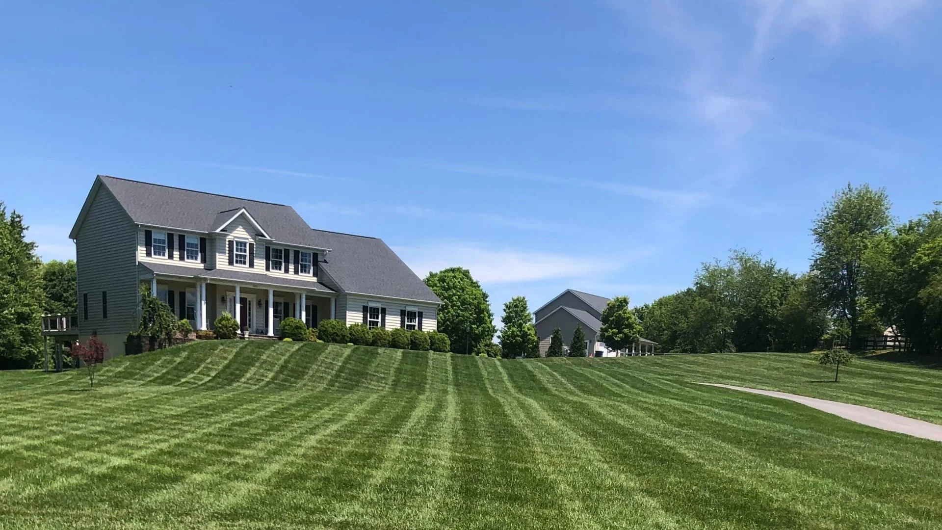 Striped lawn with large house.