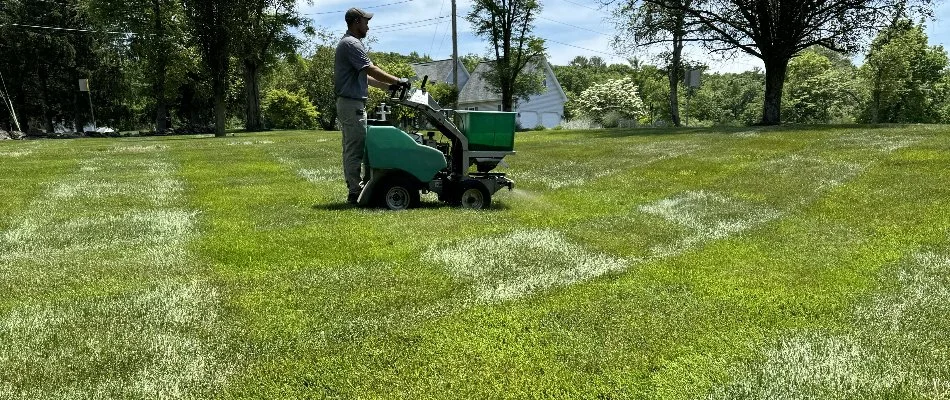 Tech going over a lawn in Westminster, MD, with a granular spreader.